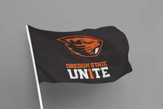 Black game-day flag carrying the Beavers logo and the Oregon State UN1TE lockup